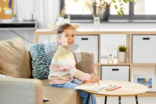 Image of little girl drawing with coloring pencils at home