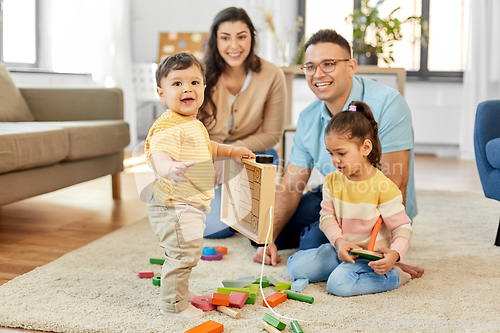 Image of happy family palying with wooden toys at home