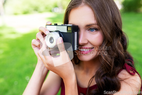 Image of happy woman with camera photographing at park