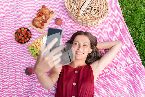 Image of happy woman with smartphone taking selfie at park