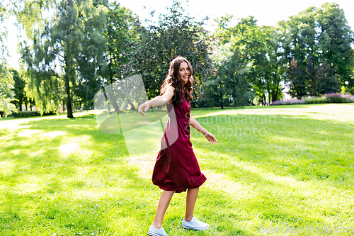 Image of happy smiling woman walking along summer park