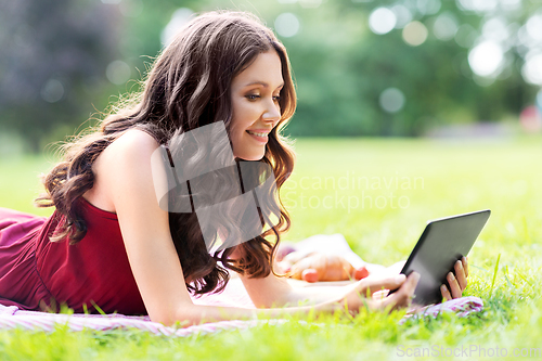 Image of happy woman with tablet computer on picnic at park