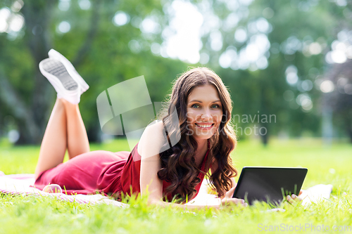 Image of happy woman with tablet computer on picnic at park