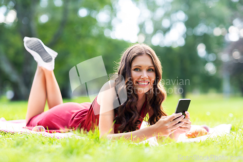 Image of happy woman with smartphone at park