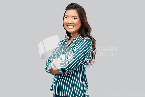 Image of happy asian woman with crossed arms on grey