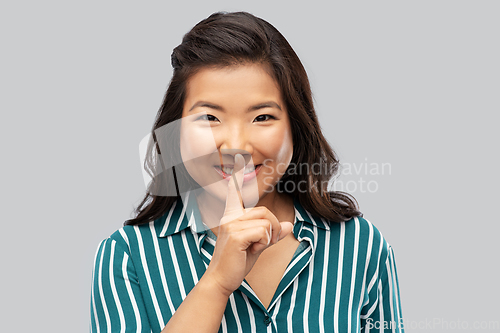 Image of portrait of happy asian woman making hush gesture