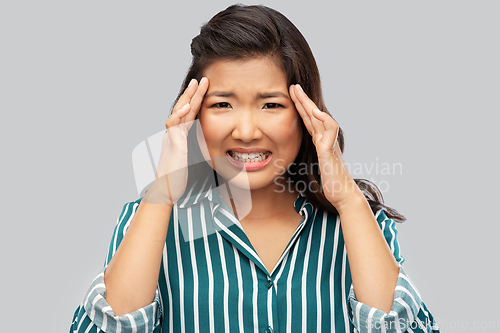 Image of stressed asian woman holding to her head