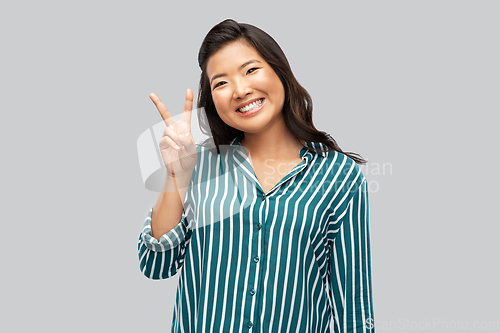 Image of happy asian woman showing peace hand sign