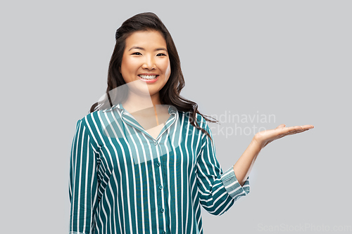 Image of happy asian woman holding something on hand