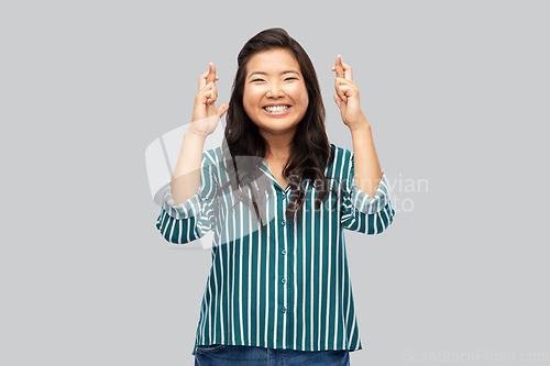 Image of happy smiling asian woman holding fingers crossed