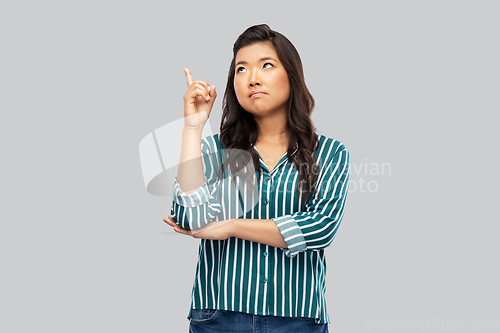 Image of asian woman pointing finger up on grey