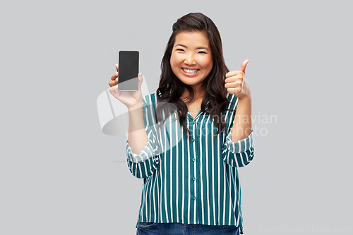 Image of happy asian woman with smartphone shows thumbs up