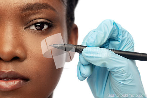 Image of face of african woman and hand with marker