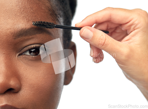 Image of face of african woman and hand with mascara brush