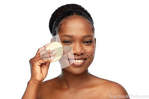 Image of young woman cleaning face with exfoliating sponge