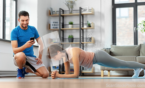 Image of woman with personal trainer doing plank at home