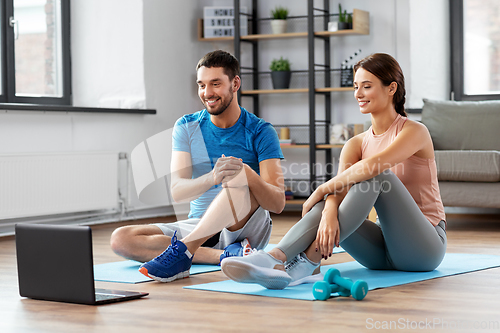 Image of happy couple with laptop doing sports at home