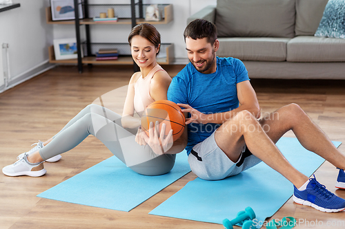 Image of happy couple exercising with ball at home