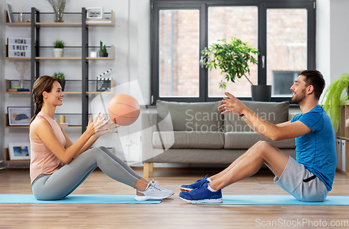 Image of happy couple exercising with ball at home