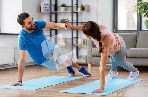 Image of happy couple make high five in side plank at home