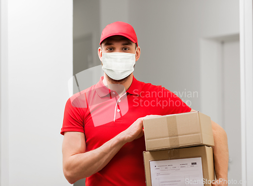 Image of delivery man in mask with parcel box in corridor