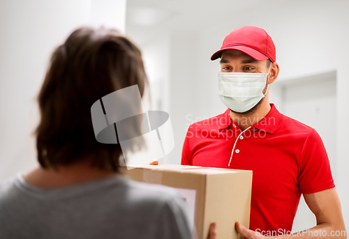 Image of delivery man in mask giving parcel box to customer