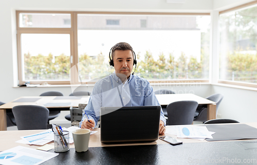 Image of man with headset and laptop working at home