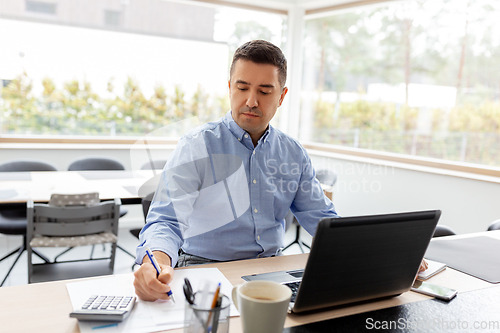 Image of man with calculator and papers working at home