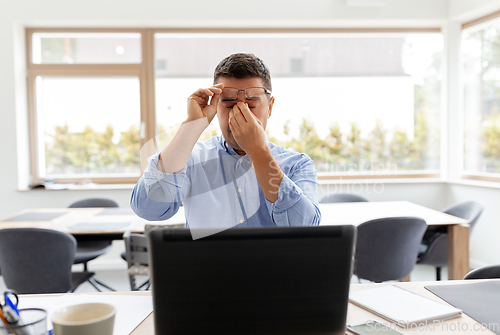 Image of tired man with laptop working at home office