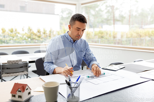 Image of architect with blueprint working at home office