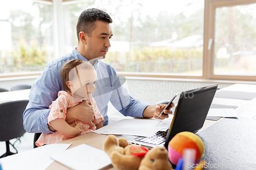 Image of father with baby and smartphone working at home