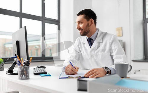 Image of smiling male doctor with clipboard at hospital