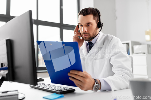 Image of male doctor with headset and clipboard at hospital