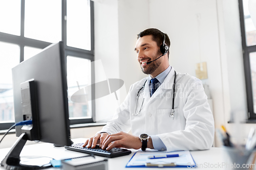 Image of happy doctor with computer and headset at hospital