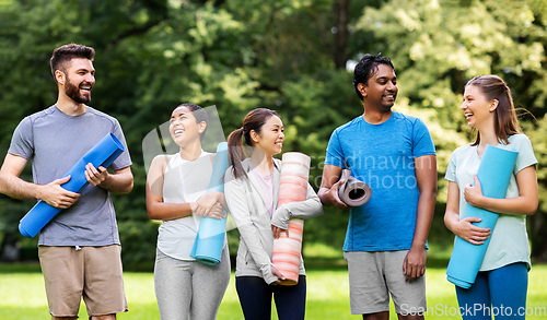 Image of group of happy people with yoga mats at park