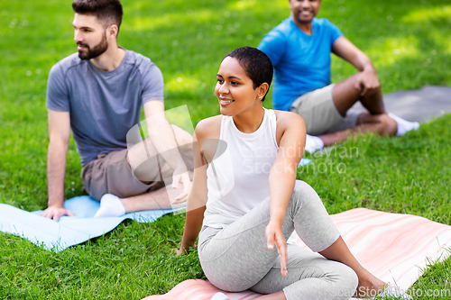 Image of group of people doing yoga at summer park