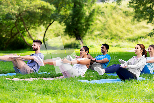 Image of group of people doing yoga at summer park