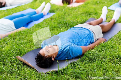 Image of group of people doing yoga at summer park