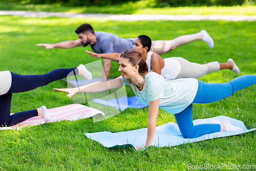 Image of group of people doing yoga at summer park