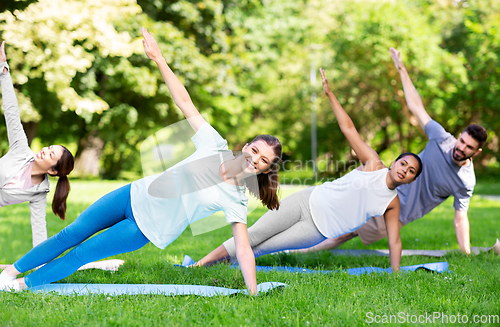 Image of group of people doing yoga at summer park