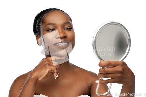 Image of smiling african american woman looking to mirror