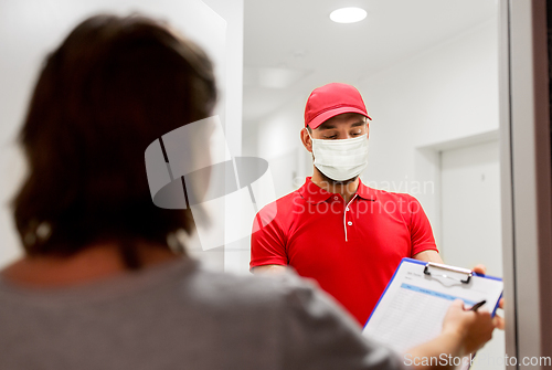 Image of delivery man in mask and customer signing papers