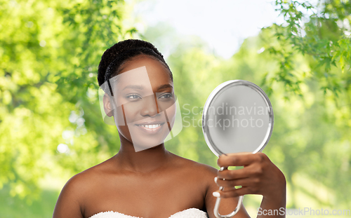 Image of smiling african american woman looking to mirror