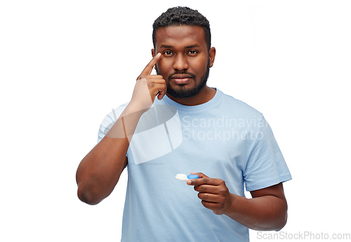 Image of young african american man applying contact lenses