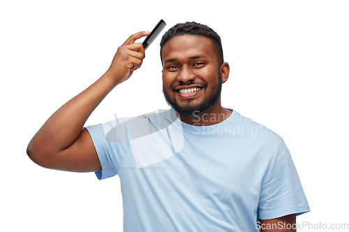 Image of happy african american man brushing hair with comb