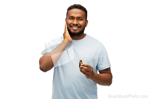 Image of african man applying grooming oil to beard