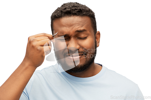 Image of african man with tweezers tweezing his eyebrow