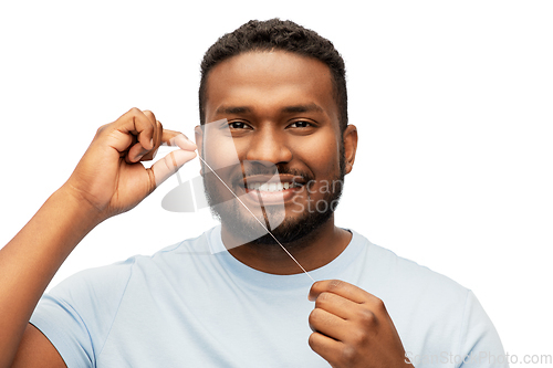 Image of happy african man with dental floss cleaning teeth