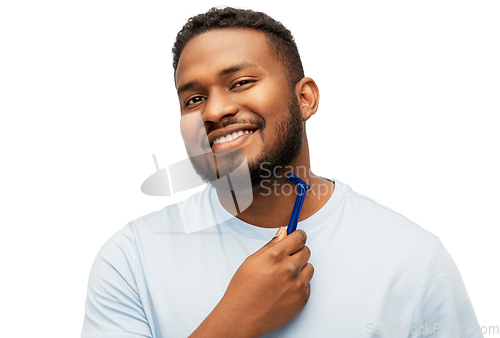 Image of smiling african man shaving beard with razor blade