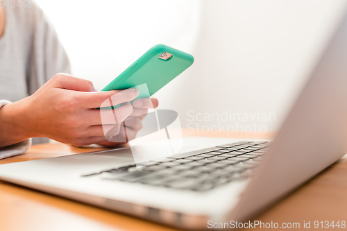 Image of Woman working on cellphone and laptop computer